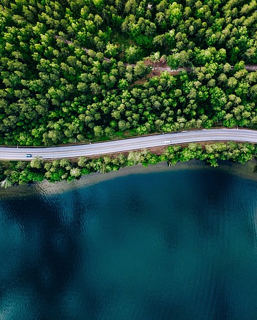 Winding road between forest and lake