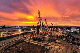 Baustelle mit Kränen bei Sonnenuntergang